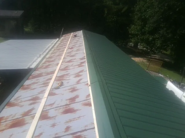 Old rusted panels beside newly installed green metal roofing — Wind Damage Roof Repair by Roofing Brothers in Menahga
