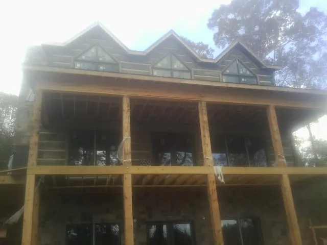 Dormers and porch framing on a large log home under construction — Roof Coating work by our crew in Menahga