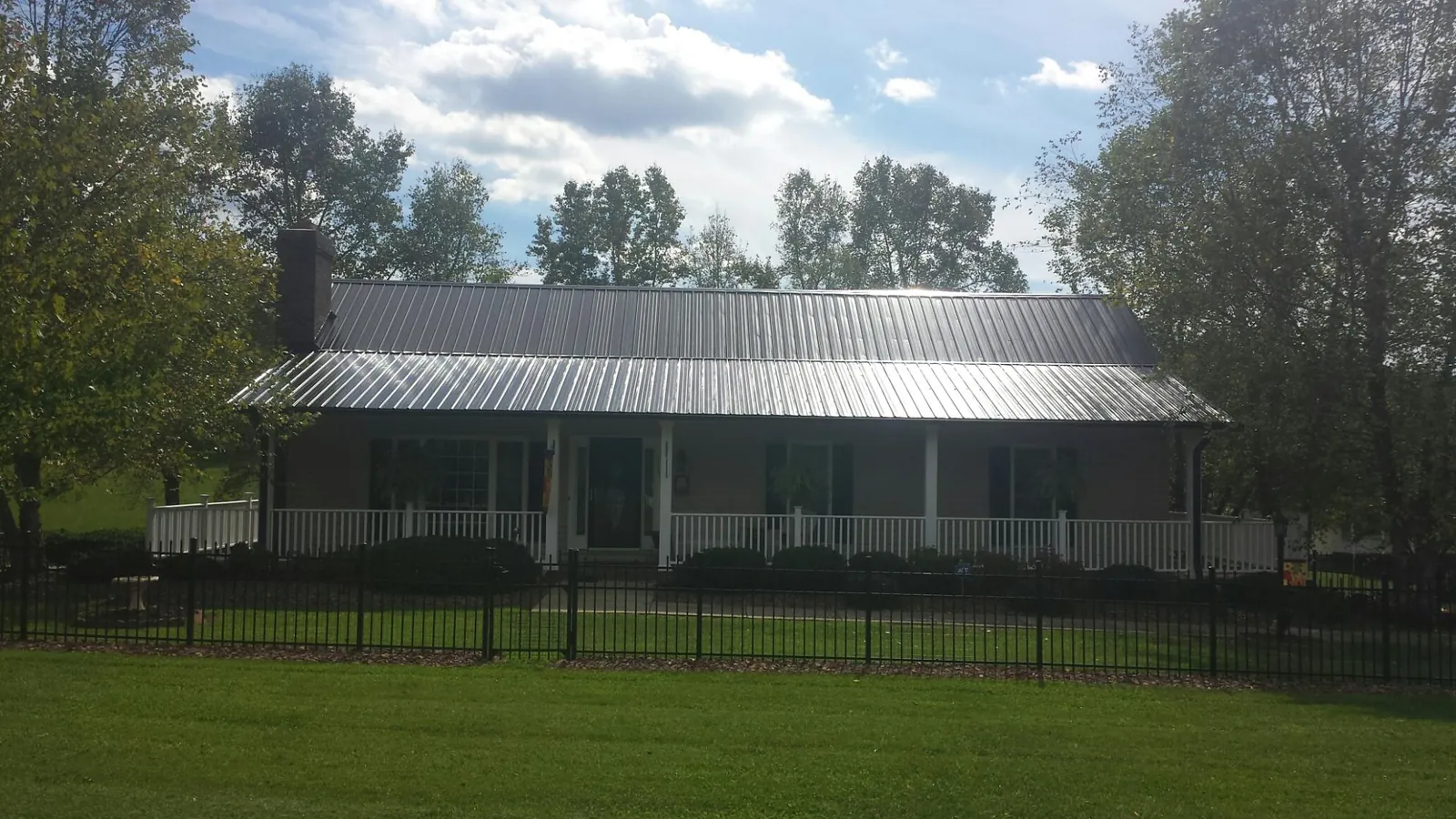 Gray metal roof on a brick ranch with a full width front porch — Gutter Guard Installation work by our crew in Menahga