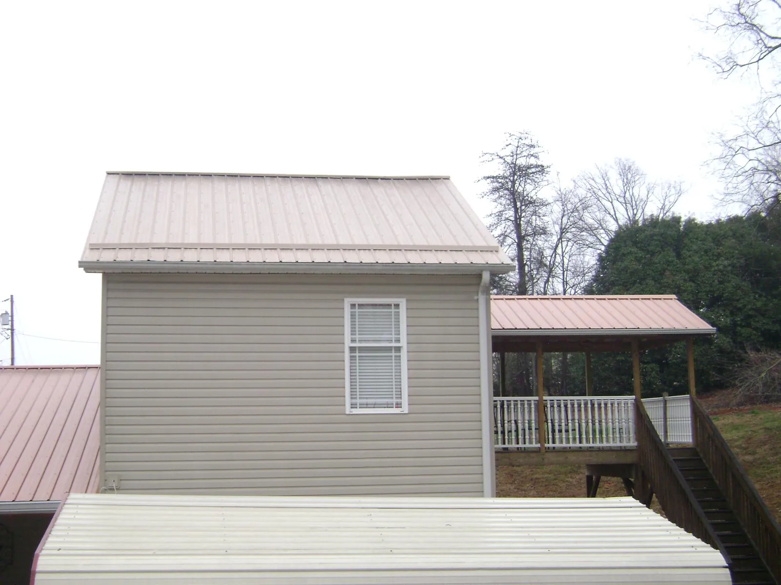Tan metal roofs on a two story addition and attached porch, from a Roof Replacement job in Menahga