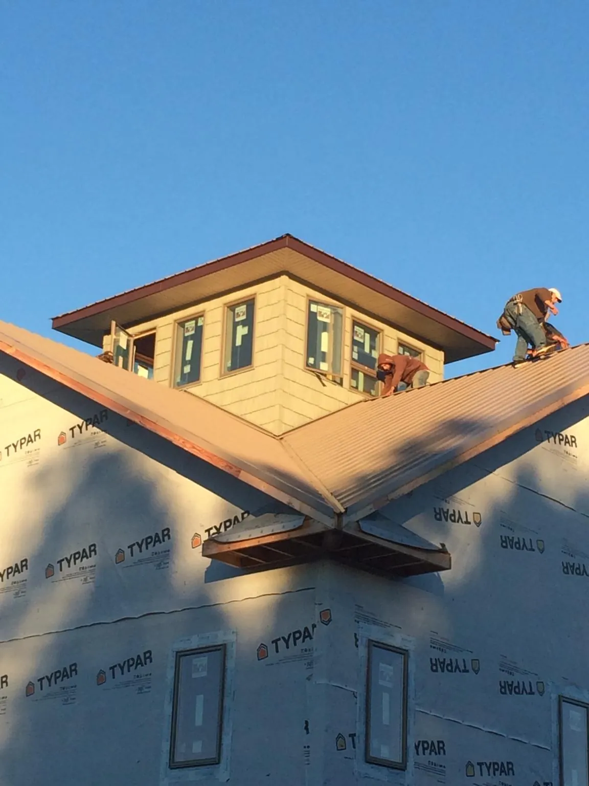Roofers working around a rooftop cupola on a new metal roof at sunset — Roof Waterproofing in Menahga by Roofing Brothers